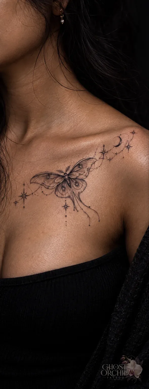Fine line luna moth tattoo across a collarbone, with a crescent moon, stars and delicate dotted trails